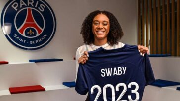 Allyson Swaby holds up her jersey as she signs her contract with Ligue 1 Feminines side, Paris St. Germain