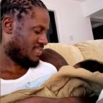 Aidonia holds his son at his home in Kingston