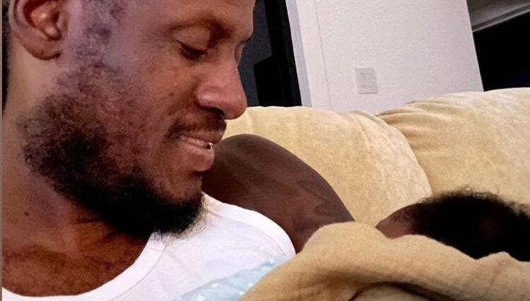 Aidonia holds his son at his home in Kingston