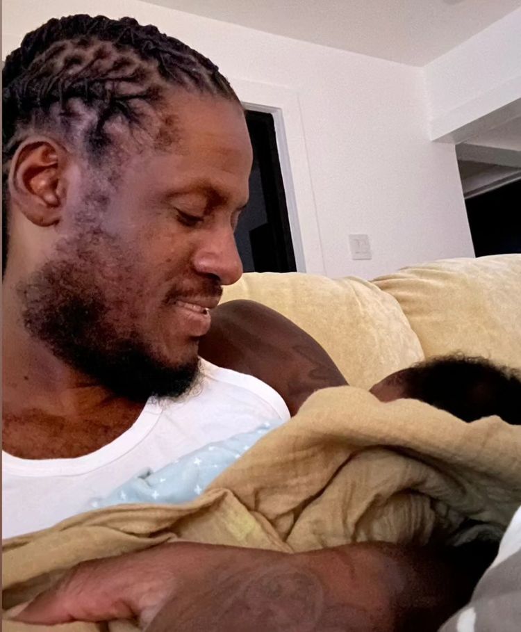 Aidonia holds his son at his home in Kingston