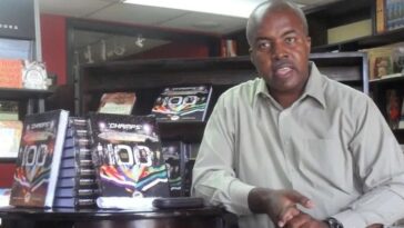 The late Hubert Lawrence posing beside his book, Champs 100.