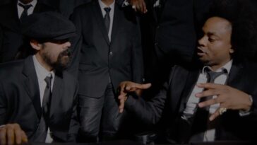 Damian Marley and Rygin King engage in conversation during the music video for 'Things Done Change.'