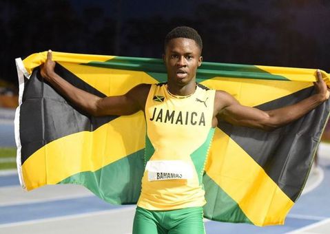 Ackeem Blake holds up the Jamaica flag following a race.