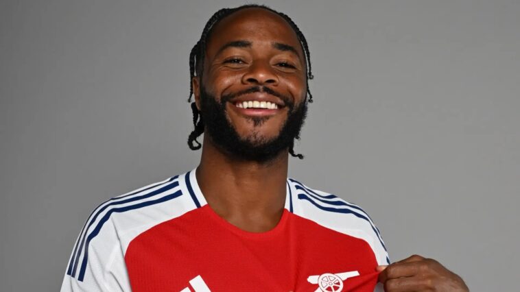 Raheem Sterling points to the cannon on his Arsenal shirt during a photoshoot.