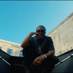 Masicka sits on top of a car in his music video for Mute.'