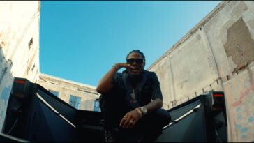 Masicka sits on top of a car in his music video for Mute.'