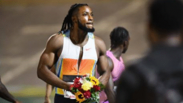 Kishane Thompson celebrates with flowers after winning men's 100m at the 2025 Racers Grand Prix