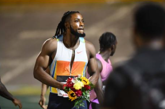 Kishane Thompson celebrates with flowers after winning men's 100m at the 2025 Racers Grand Prix