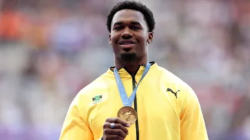 Roje Stona holds up his gold medal for Team Jamaica at the 2024 Olympics.