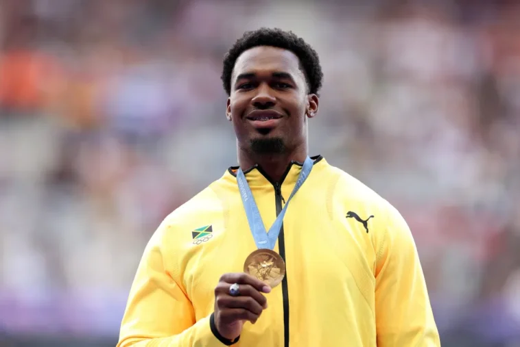 Roje Stona holds up his gold medal for Team Jamaica at the 2024 Olympics.