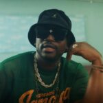 Busy Signal sits in a classroom during a music video for "Jamaica Love."