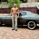 Asafa Powell, an avid car collector, poses with his vintage vehicle