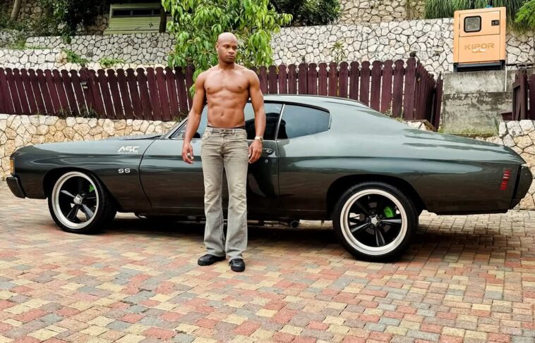 Asafa Powell, an avid car collector, poses with his vintage vehicle