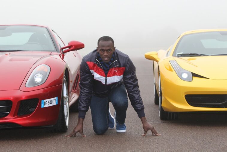 Usain Bolt gets on his mark in between two luxury Ferrari vehicles.